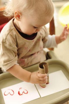 a toddler is playing with a roll of paper