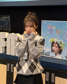 a young woman is standing in front of a sign and posing for the camera with her hands on her face