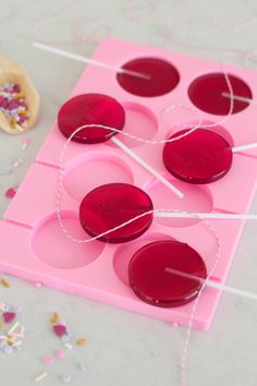 some candy pops are sitting on a pink tray