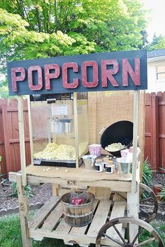 an outdoor popcorn stand with buckets full of popcorn on the side and a sign that says popcorn