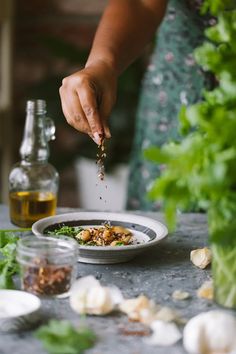 a person is sprinkling seasonings onto a bowl of food on a table