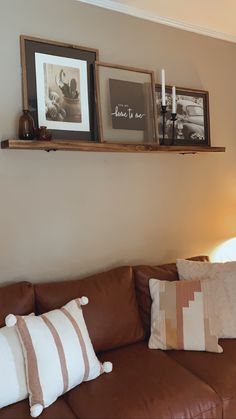 a living room with brown leather couches and pictures hanging on the wall above them