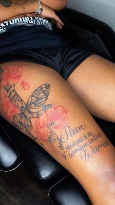 a woman laying on top of a black chair next to a butterfly and flower tattoo