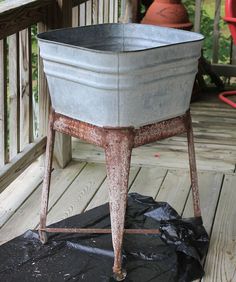 an old metal tub sitting on top of a wooden deck next to a potted plant