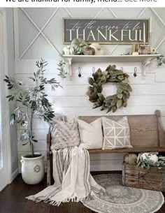 a wooden bench sitting next to a potted plant on top of a rug in front of a white wall