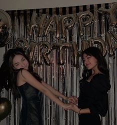 two young women standing next to each other in front of balloons