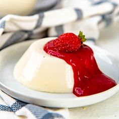 a small dessert on a white plate with strawberry sauce