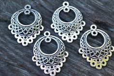 three pairs of silver toned metal earrings on a wooden surface