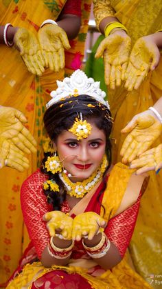 a woman dressed in yellow and red with hands painted on her face, posing for the camera