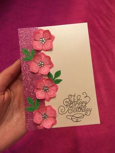 a hand holding a card with pink flowers on it and the words happy birthday written in black