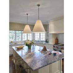 a kitchen with two lamps hanging over the island