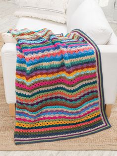 a crocheted blanket sitting on top of a white couch