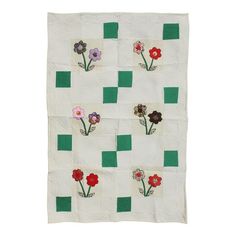 a white quilt with flowers on it and green squares around the edges that have been stitched together