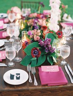 the table is set with pink and purple flowers