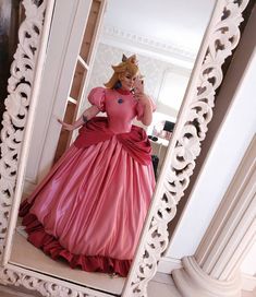 a woman in a pink dress taking a selfie in a mirror with her cell phone