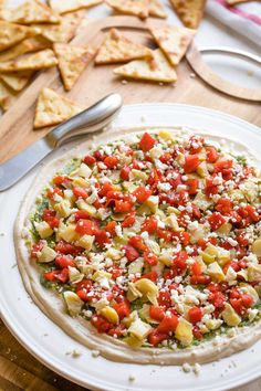 a pizza sitting on top of a white plate covered in cheese and veggies