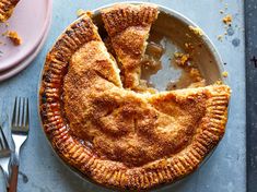 a pie with a slice missing from it on a plate next to silverware and utensils