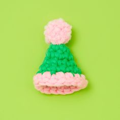 a crocheted hat on a green background with pink and green trimmings