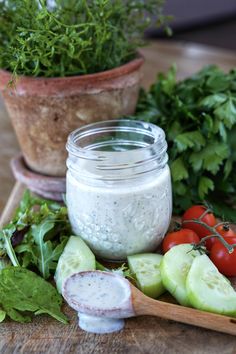 a wooden cutting board topped with cucumbers, tomatoes and other veggies