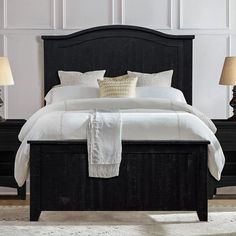 a black bed with white sheets and pillows