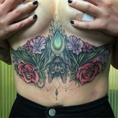 a woman's chest with flowers and a bat tattoo on her left side ribcage