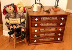 two dolls sitting on top of a wooden drawer next to a lamp and desk with drawers