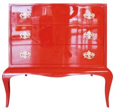 a red chest of drawers with gold handles