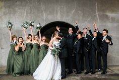 a group of people standing next to each other in front of a building holding bouquets