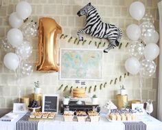 a table topped with desserts and balloons next to a zebra wallpapered wall