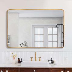 a bathroom vanity with two sinks and a large gold framed mirror on the wall above it