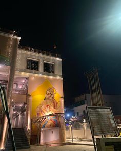 a building with a mural on the side and stairs leading up to it at night