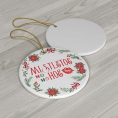 two ceramic christmas ornaments sitting on top of a wooden table next to white plates with red and green designs