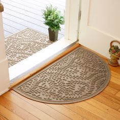 a door mat on the floor next to a potted plant in front of an open door