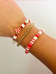 a woman's arm with three bracelets on it and candy canes in the middle