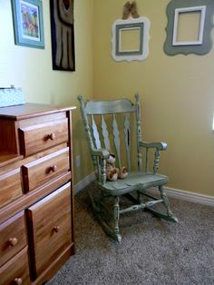 a wooden rocking chair sitting next to a dresser in a child's room with pictures on the wall