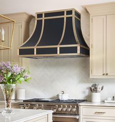 a kitchen with an oven, range hood and flowers in a vase on the counter