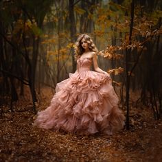 a woman in a pink dress standing in the woods