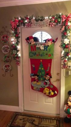 a mickey mouse christmas stocking hanging on the front door with other holiday decorations around it