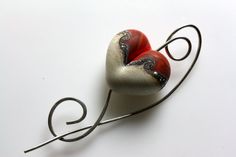 two red and white heart shaped brooches sitting on top of a metal wire