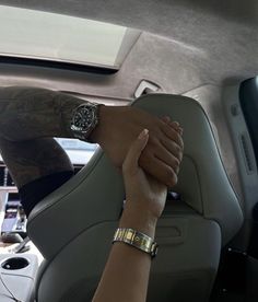 two hands on the steering wheel of a car, one holding the other's hand