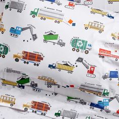 the bedding is made up with trucks and cars on white sheeting, along with matching pillow shampoos