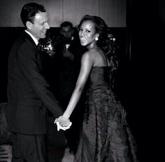 a man and woman are holding hands at a formal event in black and white photo