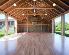 an indoor basketball court with wood flooring and ceiling lights, surrounded by large windows