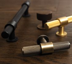 three different types of brass and black knobs on a wooden table with one metal handle