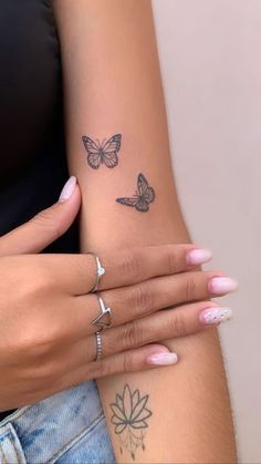 two women with tattoos on their arms and one has a butterfly tattoo on her arm