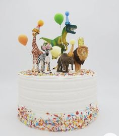 a white cake topped with lots of different types of animals and balloons on top of it