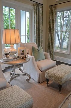 a living room filled with furniture and a lamp on top of a white table next to a window