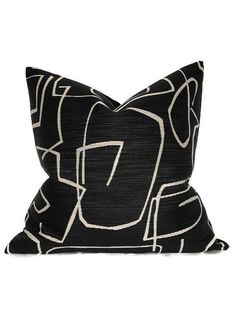 a black and white pillow with an abstract design on the front, along with a dark background