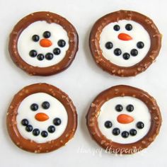 four pretzels with frosting and blueberries in the shape of a snowman