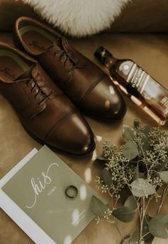 a pair of brown shoes sitting on top of a couch next to a bottle of alcohol